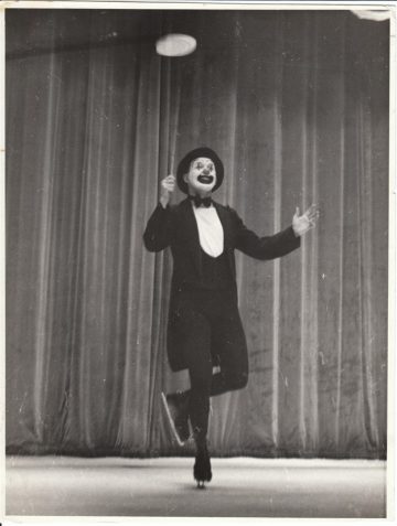 Photo of Reg Moore in clown costume on ice skates spinning a plate