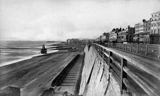 Seafront East of Chain Pier looking West, c. 1875: Seafront east of Chain Pier looking West. The sea wall on the right was built in 1827-38, with a promenade running along the top alongside the road on Marine Parade. In 1880 these wooden railings were replaced by the present cast-iron railings with dolphin motifs. | Image reproduced with kind permission from Brighton and Hove in Pictures by Brighton and Hove City Council