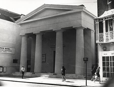 This is a photographic print made by the Borough Surveyor's department. It shows the Brighton Unitarian Church on the west side of the street. This church was built by Amon Henry Wilds in 1820. The {g:Doric}Doric{/g} pillars were reputedly inspired by the Temple of Theseus in Athens. | Reproduced courtesy of Royal Pavilion, Libraries & Museums, Brighton & Hove