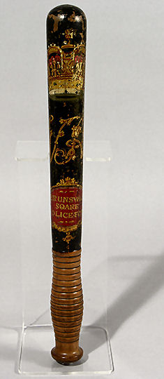This is a wooden Brunswick Square Police truncheon, with a black painted body, decorated with a painted royal crown, VR (for Queen Victoria) and 'Brunswick Square Police Force'. The truncheon was used by Jesse Burchell and was made in c1858. | Reproduced courtesy of Royal Pavilion, & Museums, Brighton & Hove
