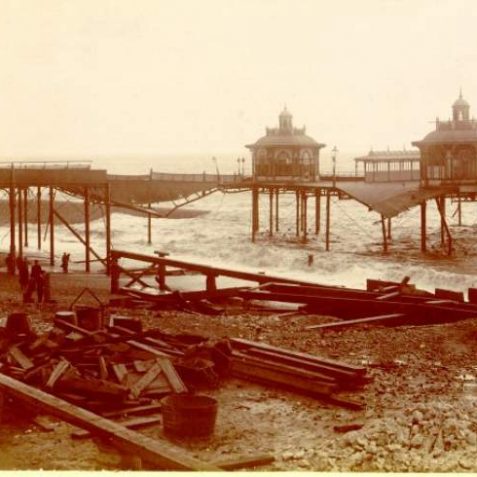 Damaged West Pier the storm of 1897,debris and onlookers can be seen on the beach. | Image reproduced with kind permission from Brighton and Hove in Pictures by Brighton and Hove City Council