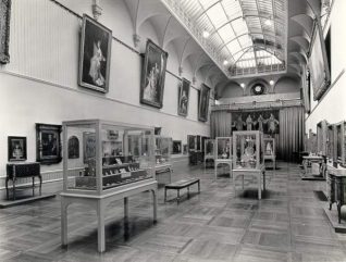 Main Gallery, Brighton Museum, c. 1965: Main gallery of Brighton Museum display cases share the space with the works of art. | Image reproduced with kind permission from Brighton and Hove in Pictures by Brighton and Hove City Council