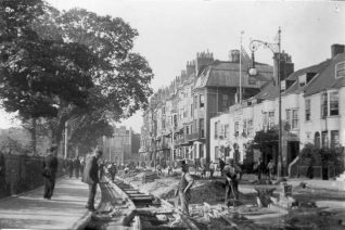 Workmen laying tram rails in Marlborough Place, opposite the King and Queen public house. The tram service began along this route on 25 November 1901, although the network was not completed until 1904. The bow-fronted Georgian King and Queen was replaced by the current red-brick timber-framed building in 1931-32. | Image reproduced with kind permission from Brighton and Hove in Pictures by Brighton and Hove City Council