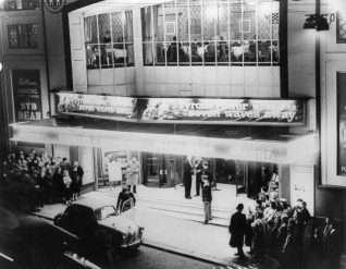 People queuing outside the Regent Cinema. Above the entrance the restaurant can be seen. A banner advertises that Tyrone Power is appearing in the film Seven Waves Away. At this time, there was ballroom dancing was evening with music by the Syd Dean Orchestra. | Image reproduced with kind permission from Brighton and Hove in Pictures by Brighton and Hove City Council