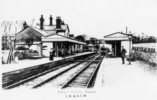 Falmer Station, c. 1905: People waiting on the platforms of Falmer Station as a train approaches the station. At this time the station was part of the London, Brighton and South Coast Railway. Falmer Station opened on 8 June 1846 on the eastern side of the village when the railway line opened, and reopened on 1 August 1865 at the current site. In 1890 the station was rebuilt with an integrated station-master's house within the building. | Image reproduced with kind permission from Brighton and Hove in Pictures by Brighton and Hove City Council